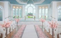 Disney's Wedding Pavilion, featuring pews, a ceremony table with a floral arrangement, cherry blossom arrangements and flower petals strewn down the aisle